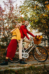 Bearded guy with blonde girl sitting on bike in park