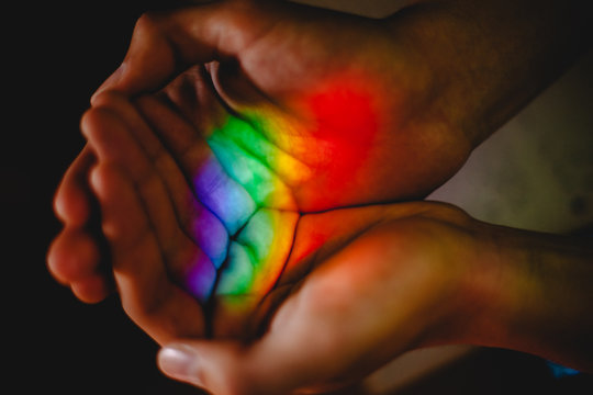 Teenage boy holding rainbow in his hands