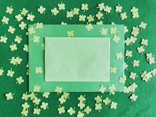 St. Patrick's Day background concept. Green clovers from paper and envelope on a green background....