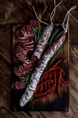 Fuet, a traditional Spanish sausage with rosemary. Slice sausages. Rosemary. Top view. Free space for your text.