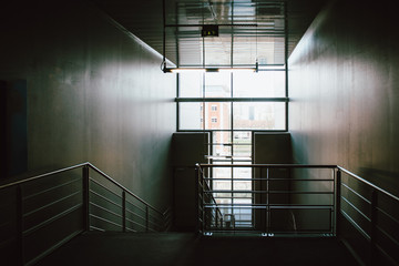 Abstract empty corridor with large downward staircase and large glass facade