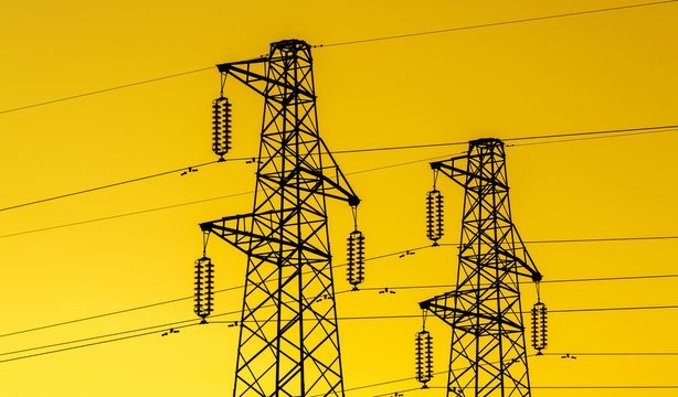 lectric power industry. Transmission towers or electricity pylons with golden sky background