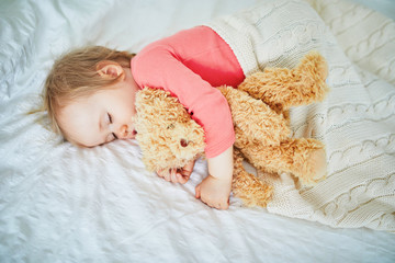 Adorable baby girl sleeping with her favorite toy