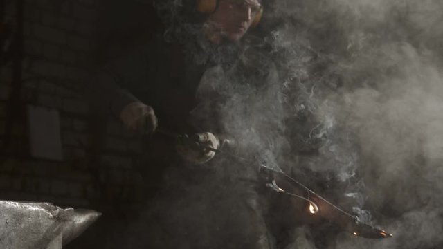 Blacksmith cooling out hot knife - steam comes off the burning blade