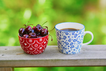 Cup of black coffee and bowl of cherries
