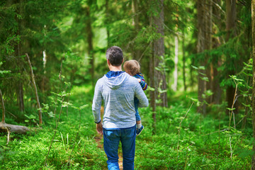 Father carrying his child during walk in forest