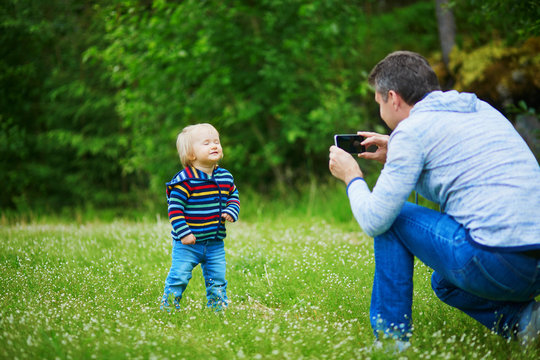 Father taking photo of his daughter during walk in forest
