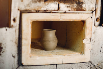 Man use a clay oven. Oven for clay. Man pust a jug inside
