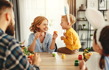 Happy easter! family mother, father and children paint eggs for holiday.