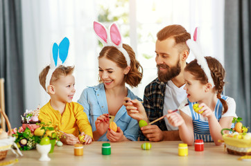 Happy easter! family mother, father and children paint eggs for holiday.