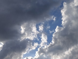 Blue sky with gray and white clouds at sunset, background, unstable changeable weather.