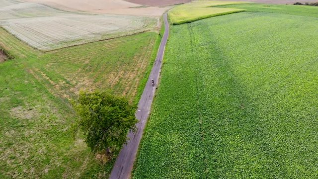 Aerial view of motorcycle on a small road next to agriculture field. Walloon Brabant, Belgium.