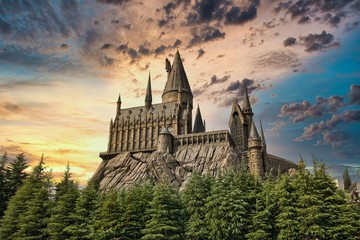 Naklejka premium OSAKA, JAPAN - AUGUST 10, 2019: Hogwarts Castle under dramatic sun set sky. The Wizarding World of Harry Potter in Universal Studios Japan (USJ). USJ is a fun and famous theme park in Osaka, Japan.