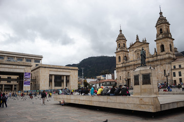 Fototapeta na wymiar People in Bolivar Square in middle of Downtown. Catedral Primada at right and Palacio de Justicia left of the capture Monserrate church at background.