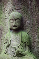 Fototapeta na wymiar Stone statue of smiling Jizo-bosatsu (Ksitigarbha)