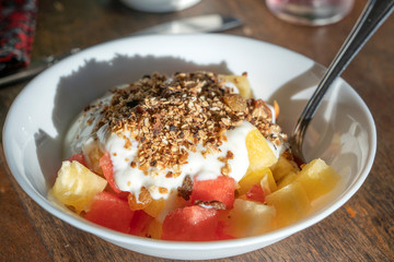 Healthy vegetarian breakfast bowl with yogurt, muesli cereals, watermelon and pineapple