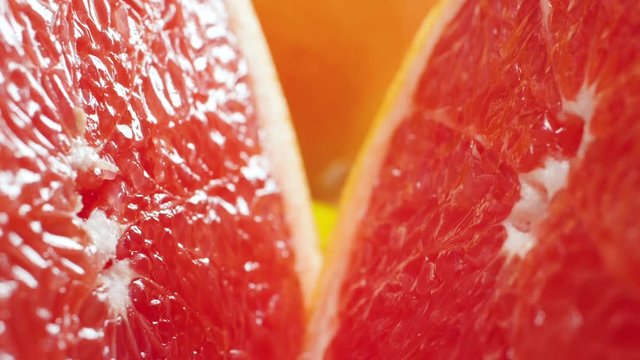Closeup video of camera moving between two halves of freshly cut orange or grapefruit. Perfect abstract shot for organic food and healthy nutrition. Closeup of citrus fruits