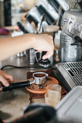 Barista pressing ground coffee into portafilter by tamper to making coffee.Coffee machine preparing fresh coffee. Closeup of filter holder with ground powder on bar coffee maker. and pouring into whit