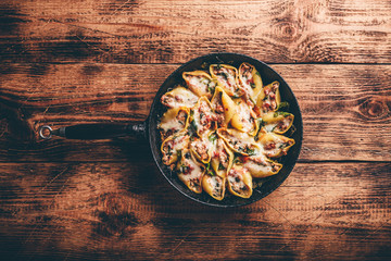 Skillet of baked jumbo shells pasta stuffed with ground beef, spinach and cheese