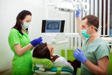 Young Dentist treating a female Patient in the dental studio