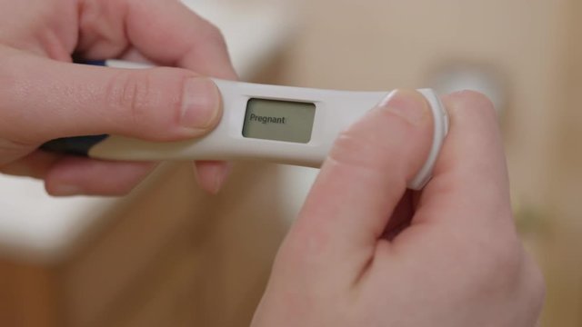 Positive Pregnancy Test held by Woman, test says the actual word 'Pregnant'