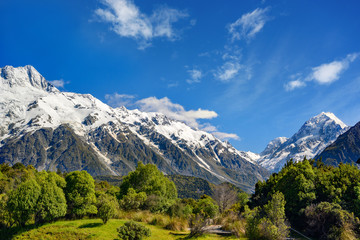 Fototapeta na wymiar High mountain views on the top of the mountain are white snow in the summer with sky and clouds with green grass throughout the area in Mount Cook National Park in the island south of New Zealand.