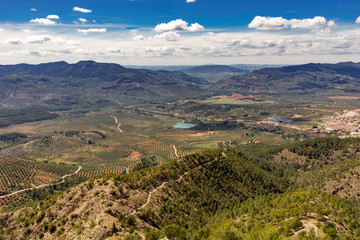 Paisaje de un valle entre montañas con campo, cultivos, poblados y cielo azul