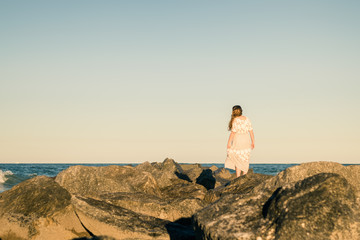 Naklejka na ściany i meble Girl Standing on Rocks with Ocean Horizon in Background