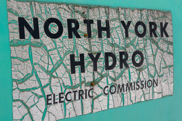 Ancient green sign for North York Hydro on an abandoned junkyard truck