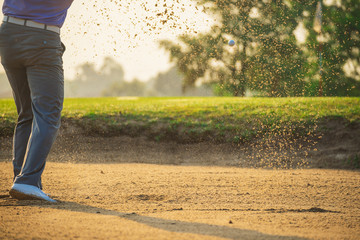 Golfers exploding sand in the bunker..