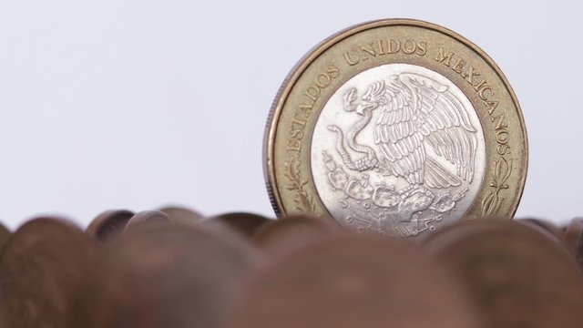 Commemorative 100 pesos coin spinning over old mexican coins