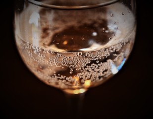 glass of wine with bubbles on black background.