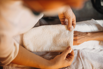 Confident spa worker is using a towel during a skin care procedure for hands