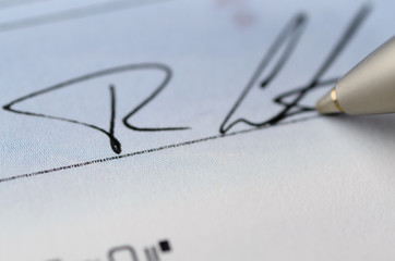 Close up of pen signing a cheque with microprint security features