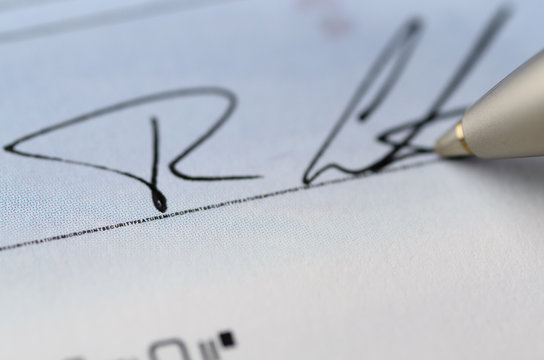 Close Up Of Pen Signing A Cheque With Microprint Security Features