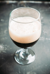 Freshly brewed dark beer on the black rustic background. Selective focus. Shallow depth of field.