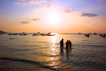 Fototapeta premium Tourist family are enjoy swimming on sea in evening time before sun set.silhouette group of people in relax time with seascape,cloud sky nature .