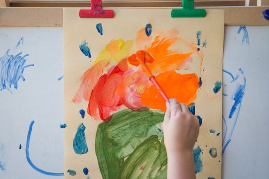 Child Painting Paper Clipeed To An Easel