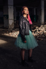 Portrait of a young girl with pink hair standing next to the bricks in a collapsed building