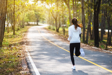 Rear view image of a young asian woman jogging in city park in the morning