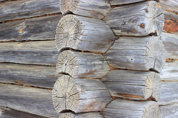 Close-up of the outer wall of an old wooden structure cut down from logs. The logs from time to time have a lot of cracks.