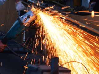 worker grinding cutting metal sheet with grinder machine overwrites the master of welding seams angle grinder and sparks. Electric grinder in the industrial workshop.