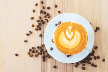 hot latte coffee in white ceramic cup on wooden table in coffee shop