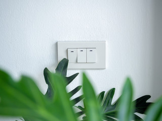 Three white light switch on white concrete wall.