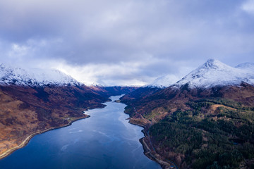 Naklejka na ściany i meble aerial drone shot of winter in glencoe and and loch Leven in the argyll region of the highlands of scotland showing clear bright white snow on the mountains of glencoe and the surrounding region