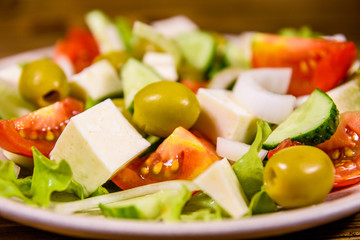 Ceramic plate with greek salad on wooden table