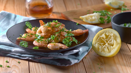 shrimp in a black plate with lemon and green onions