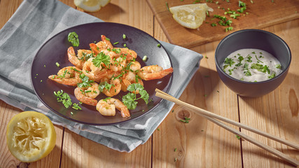 shrimp in a black plate with lemon and green onions
