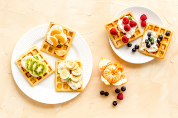 Belgian waffles with creamy cheese and berries on beige background top-down