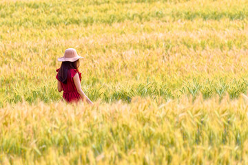 Beautiful girl enjoying nature on the wheat field at sunset light.